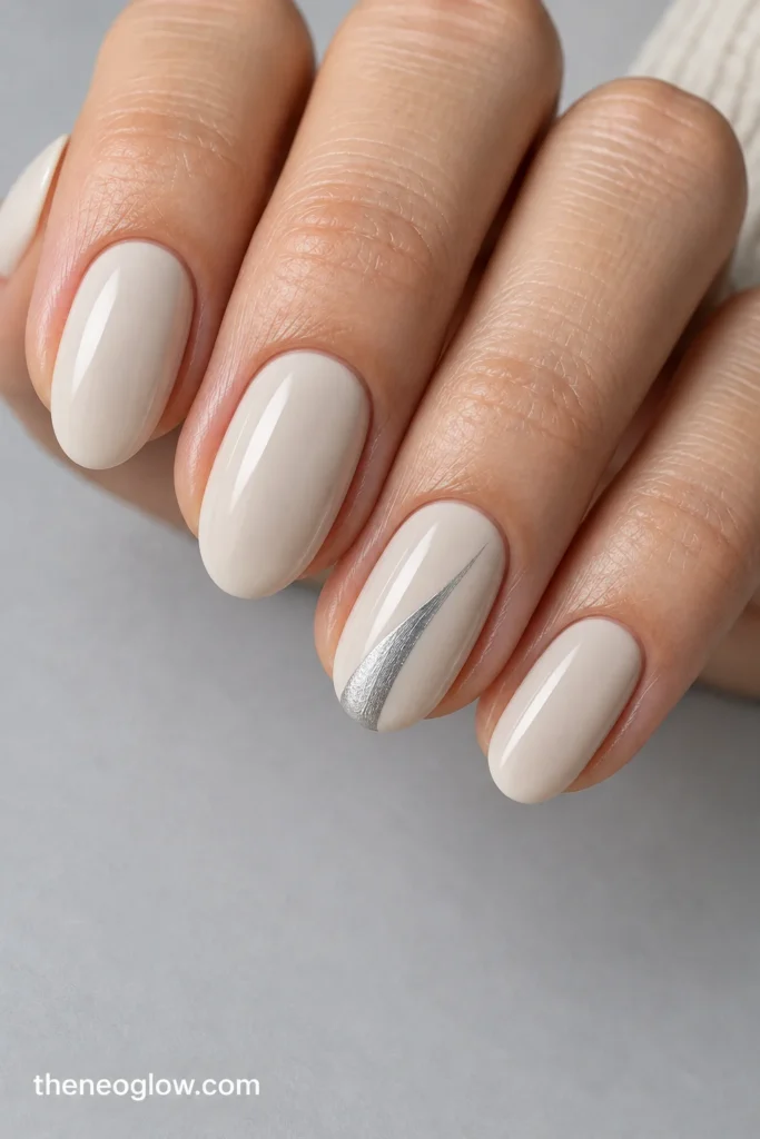 Short-to-medium soft almond oat-milk nails with one flat silver side swipe on the ring nail.
