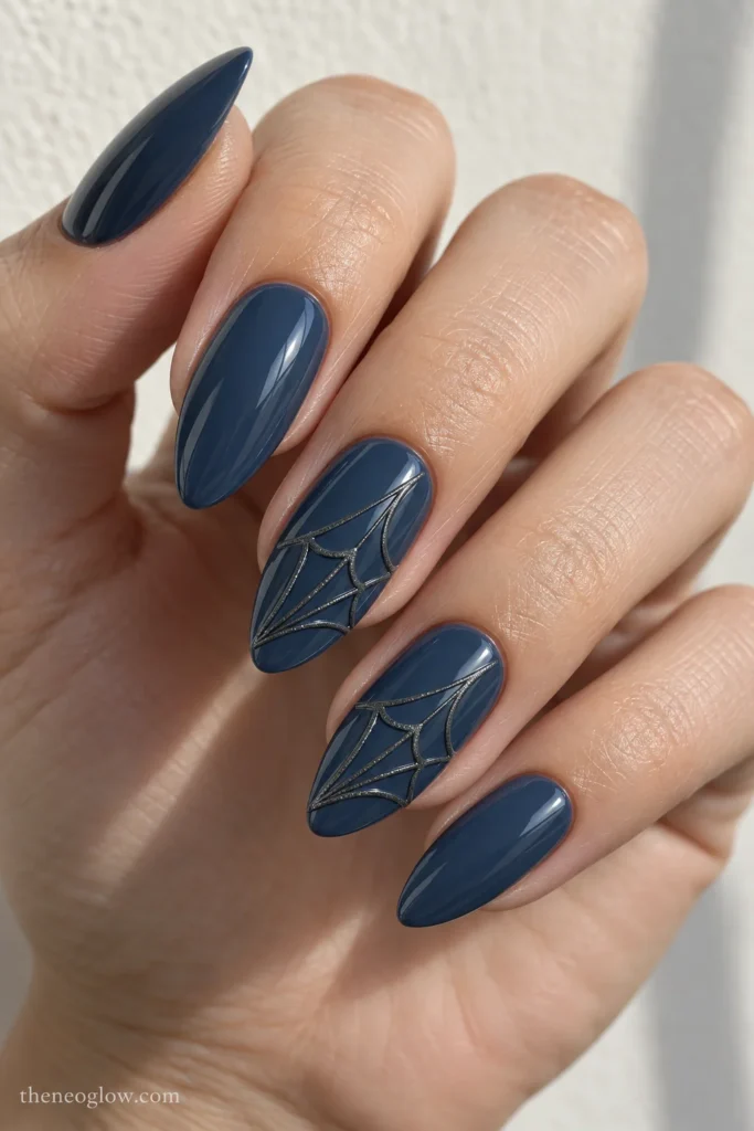 Long almond glossy slate-blue nails with subtle raised graphite spiderwebs running diagonally across middle and ring nails.
