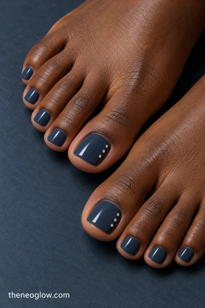 Blue-charcoal toenails with three small silver sparkle points along the outer edge of each big toenail.