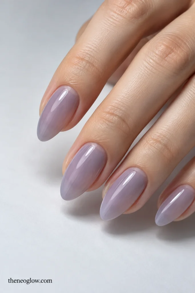 Medium almond nails with a transparent lavender-gray veil and glossy natural-looking depth.