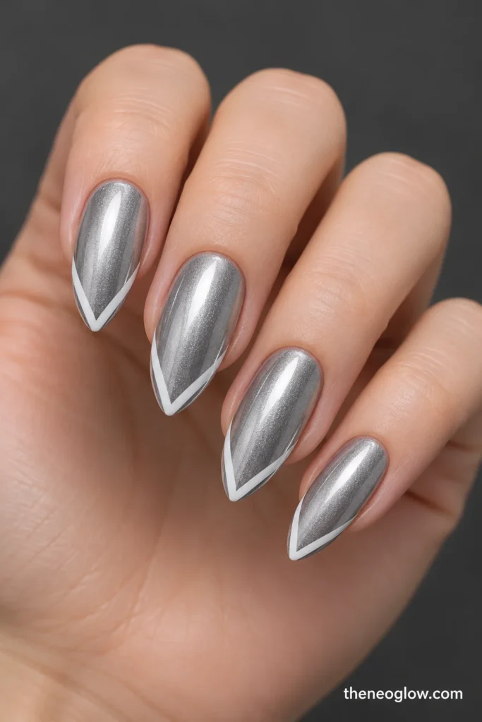 Long polished-silver almond nails with narrow white chevrons meeting at the tip centers.