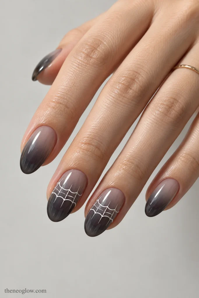 Medium oval smoky-gray gradient nails with a white spiderweb stretching horizontally across two accents.